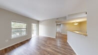 This single-floor, 3-bedroom, 1-bathroom unit offers a well-organized layout designed for comfortable everyday living. The open-concept main area seamlessly connects the living room, dining space, and kitchen, all finished with warm hardwood-style flooring that runs throughout the common areas. Natural light pours in through large windows and a sliding glass door that opens to a private balcony, providing pleasant outdoor views.

The kitchen is equipped with white cabinetry, a refrigerator, an electric range, and a peninsula-style breakfast bar with a built-in sink — ideal for casual dining or meal prep. Skylights above the kitchen enhance the bright, airy atmosphere of this central hub.

The three bedrooms offer a mix of flooring options: the primary bedroom features hardwood-style floors and direct balcony access through a sliding glass door and a dedicated window for ample natural light, while the additional bedrooms are carpeted and include ceiling fans and windows with outdoor views.

The full bathroom is thoughtfully appointed with a tub-shower combination, a single-sink vanity with storage cabinetry, and a wide mirror with overhead lighting. A closet provides additional storage within the unit. Throughout, the neutral color palette and clean finishes contribute to a cohesive, move-in-ready aesthetic.