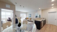 Located at 67–115 W Washington St in Oswego, Illinois, this single-floor residence offers a thoughtfully designed open-concept layout that seamlessly connects the kitchen, dining, and living areas. Light wood-style flooring flows throughout the main living spaces, complemented by neutral wall tones that create a bright and welcoming atmosphere.

The kitchen is equipped with dark espresso cabinetry, granite countertops, stainless steel appliances including a gas range, microwave, and refrigerator, and ample storage. A peninsula counter connects the kitchen to the dining and living areas, enhancing the open flow of the space. The dining area accommodates a glass-top table, while the living room features a large sectional sofa and a floor-to-ceiling vertical blind window treatment that allows generous natural light.

The bedroom is carpeted and generously sized, featuring a window with blinds, neutral walls, and ample space for full bedroom furnishings. The bathrooms are finished with granite-topped dark vanities, undermount sinks, large mirrors, and wood-style flooring, offering a clean and modern aesthetic. A dedicated bathroom includes a toilet, towel bar, and well-organized vanity area. Overall, the residence presents a cohesive, contemporary design with quality finishes throughout.