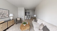 This single-floor residence at 25 Jerome Ave in Bloomfield, CT offers a thoughtfully designed open-concept layout with a clean, modern aesthetic. The living area serves as the heart of the home, featuring light-toned hardwood flooring, neutral white walls, and a large window that invites generous natural light while offering views of the surrounding community. The space comfortably accommodates a seating arrangement centered around a herringbone-patterned coffee table, complemented by an open lean-to shelving unit that adds a warm, industrial touch.

The layout flows seamlessly from the living area into the kitchen, which features dark cabinetry, stainless steel appliances, and a breakfast bar with seating — ideal for casual dining or entertaining. Adjacent to the living space, a dedicated dining area benefits from a large sliding glass door with a transom window above, filling the room with light and providing direct outdoor access.

The bedroom area offers a spacious feel with a double-door closet providing ample storage. A hallway connects the main living spaces, maintaining a clean and functional flow throughout. The bathroom includes a full tub-shower combination with white tile surround, a dark-vanity with an integrated sink, a large mirror, and contemporary wall-mounted lighting, completing this well-appointed residence.