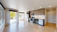 Located at 701 5th Avenue North in Seattle's Lower Queen Anne neighborhood, this thoughtfully designed unit offers a clean, contemporary aesthetic throughout. The open-concept living and kitchen area is anchored by expansive windows that flood the space with natural light and frame views of the surrounding Seattle cityscape. A sliding glass door leads to a private balcony, seamlessly extending the living area outdoors.

The kitchen is well-appointed with stainless steel appliances including a refrigerator, electric range, over-the-range microwave, and dishwasher. Warm wood-toned cabinetry extends to the ceiling, complemented by a classic white subway tile backsplash and light countertops. Light hardwood-style flooring runs throughout the main living areas, adding warmth and continuity.

The bedroom features plush carpeting and ample space, while the hallway provides generous storage with a dedicated pantry closet and a spacious reach-in closet complete with a hanging rack. Two bathrooms serve the unit — one with a tiled shower and a modern vanity with city views, and a second featuring a full soaking tub/shower combination. An in-unit washer and dryer stack is also present, adding everyday convenience to this well-equipped Seattle residence.