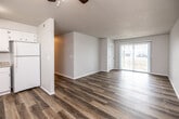 This single-floor unit showcases a clean, functional layout highlighted by wood-look plank flooring that runs consistently throughout the space, lending a cohesive and modern feel. The open-concept design connects the kitchen and living area seamlessly, creating a spacious and versatile environment.

The kitchen is well-appointed with white cabinetry offering ample upper and lower storage, granite-style countertops, a double-basin sink, and white appliances including a coil-top electric range, dishwasher, and refrigerator. A range hood above the stove adds practical ventilation. The textured ceiling and ceiling fan with integrated lighting are present in this area as well as throughout the unit.

The living area is generously sized, with neutral walls, a sliding glass door that introduces natural light and provides outdoor access, and a ceiling fan overhead. A dedicated electrical panel is also accessible within this space.

The bedrooms are comfortably proportioned, each featuring wood-look flooring, ceiling fans, and windows with blinds that allow for natural light and outdoor views.

The bathroom includes a white vanity with granite-style countertop, a large mirror, and a combined shower-tub unit, all finished with consistent wood-look flooring for a unified aesthetic throughout the home.
