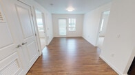 This single-floor residence at 21215 International Blvd in Des Moines, Washington, offers a clean, contemporary design with a thoughtful layout. The open living area is finished with warm wood-style flooring that extends throughout the main living and kitchen spaces, creating a cohesive and inviting atmosphere. Crisp white walls and flush-mount lighting keep the interior bright and neutral throughout.

The kitchen is a functional standout, featuring rich dark espresso cabinetry with sleek hardware, light-toned countertops, and a full suite of black appliances including a gas range, built-in microwave, dishwasher, and refrigerator. Ample upper and lower cabinet storage makes the space highly practical. A double-basin sink sits along the counter, and the open sightlines connect the kitchen directly to the living area.

The living room benefits from a glass door leading to a private balcony, providing natural light and outdoor views of the surrounding landscape. The bedroom spaces are carpeted for comfort and each include windows with vertical blinds that allow adjustable natural light while maintaining privacy.

The overall design balances modern finishes with everyday functionality, presenting a well-maintained, move-in-ready space in a convenient Des Moines location.