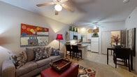 This well-appointed one-bedroom, one-bathroom residence in Bentonville, Arkansas offers an efficient and comfortable single-floor layout. The open-concept living and kitchen area serves as the heart of the home, with carpet flooring in the living space and tile flooring in the kitchen. Ceiling fans are present throughout, enhancing comfort year-round. The living room provides ample space for seating and features a front-facing window that invites natural light. The kitchen is thoughtfully designed with white cabinetry, a full suite of appliances including a dishwasher, refrigerator, microwave, and range, along with a convenient breakfast bar with seating for two — ideal for casual dining. A double sink and generous counter space complete the kitchen's functional layout. The bedroom is a comfortable retreat, featuring plush carpet flooring, a ceiling fan, and a window providing natural light. It is complemented by a dedicated walk-in closet outfitted with wire shelving and hanging rods for organized storage. The bathroom features tile flooring, a vanity with storage cabinetry, a large mirror, and overhead lighting. Throughout the space, a neutral color palette and consistent finishes create a cohesive and inviting atmosphere.