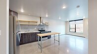 This contemporary one-bedroom, one-bathroom unit at 310 Main Ave in Fargo, North Dakota offers a thoughtfully designed layout with a clean, modern aesthetic throughout. The polished concrete floors flow seamlessly across the entire space, lending an industrial-chic character that ties each room together.

The open kitchen is a standout feature, equipped with stainless steel appliances including a refrigerator, electric range, dishwasher, and built-in microwave. Dark cabinetry contrasts elegantly with white countertops, while a subway tile backsplash and open natural wood floating shelves add warmth and texture. A stainless steel island work table provides additional prep space and visual interest. A bold range hood anchors the cooking area.

The bedroom is a comfortable, well-proportioned retreat featuring a large picture window with black-framed trim that frames views of the surrounding Fargo streetscape and fills the room with natural light. A ceiling fan adds both style and function. The closet provides convenient dedicated storage.

The bathroom area includes dark modern cabinetry with ample storage, and the unit benefits from the practical addition of an in-unit stacked washer and dryer. Recessed lighting throughout ensures a bright, well-lit environment. The unit's efficient, open floor plan makes excellent use of every square foot, making it an ideal urban residence in downtown Fargo.