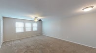 This single-story, two-bedroom, one-bathroom residence offers a practical and well-organized layout designed for comfortable everyday living. The living area is generously sized, featuring neutral-toned carpet, soft gray walls, and a ceiling fan with light fixture. A bank of windows along one wall allows natural light to fill the space, creating a bright and open atmosphere.

A defining architectural detail is the pass-through window connecting the living area to the kitchen, complete with a granite-style ledge that adds a casual dining or serving element. The galley-style kitchen is efficiently designed with dark espresso cabinetry, light granite countertops, a stainless steel double sink, and black appliances including a range and refrigerator. Light wood-look tile flooring runs throughout the kitchen and entry areas.

Both bedrooms are carpeted and mirror the living area's neutral palette, each featuring a ceiling fan with light and a window fitted with blinds for natural light and privacy. The full bathroom includes a tub-shower combination with a white surround, wood-look tile flooring, and granite-style countertop detailing, maintaining a cohesive aesthetic throughout the home.