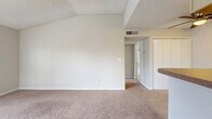 Located at 5575 Rosebriar Way in Orlando, FL, this one-bedroom, one-bathroom unit offers a well-organized layout across a single floor. The combined living and dining area is a standout, featuring vaulted ceilings with exposed beam detailing, a textured ceiling, and soft carpeting throughout. A tile-surround wood-burning fireplace with a white mantel serves as the focal point of the living room, flanked by windows that allow natural light to filter in. A ceiling fan overhead adds both function and comfort to the space.

The galley-style kitchen is efficiently designed with light wood-tone flooring, ample cabinetry on both sides, a full suite of black appliances including a range and refrigerator, a double sink, and a dedicated closet for additional storage. A breakfast bar connects the kitchen to the living area, enhancing the open feel.

The bedroom is a comfortable, carpeted retreat with a textured ceiling, a door leading to a private outdoor area, and access to a dedicated closet. The bathroom features a clean, white-tiled tub-shower combination with updated fixtures. A hallway connects the main living spaces, completing this practical and cozy floor plan.
