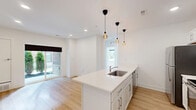 Located at 3981 Westcreek Drive in Troy, Michigan, this thoughtfully designed 2-bedroom, 2-bathroom single-floor residence offers a clean, modern aesthetic with bright white walls and light wood flooring carried consistently throughout the space. The open-concept kitchen and living area serves as the heart of the home, anchored by a large kitchen island with a white quartz countertop and integrated stainless steel sink. White shaker cabinetry pairs with stainless steel appliances, while a trio of Edison-style pendant lights adds a stylish, contemporary touch. Sliding glass doors in the living area fill the space with natural light and provide direct outdoor access to a landscaped exterior view. The two bedrooms are well-proportioned and bright, each featuring large windows that invite natural light and offer views of the surrounding community. Both rooms include closet storage, and the primary bedroom is served by a full bathroom featuring a wide white vanity, extended mirror, and a glass-enclosed tub-shower combo. The second bathroom offers a streamlined vanity with a vessel sink and a bright window. A hallway, utility room, and multiple closets round out the functional layout, making this residence as practical as it is polished.
