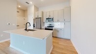 Located at 820 S Kings Ave in Brandon, Florida, this single-story home offers a clean, modern aesthetic defined by a neutral color palette, light wood-look flooring, and an open, airy layout. The open-concept living and kitchen area forms the heart of the home, where natural light filters in through windows and recessed lighting supplements the bright, welcoming atmosphere. A ceiling fan anchors the spacious living area, which flows seamlessly toward the kitchen.

The kitchen is well-appointed with gray shaker-style cabinetry accented by matte black hardware, white quartz countertops, and a classic white subway tile backsplash. A central island features a deep undermount sink with a matte black pull-down faucet, providing additional prep space and a natural gathering point. Stainless steel appliances, including a refrigerator, electric range, and over-the-range microwave, complete the functional setup.

The bedrooms feature plush carpet flooring and vaulted-style ceilings that lend a sense of openness. One bedroom offers a picturesque window with views of a neighboring waterway, filling the space with natural light. The bathroom is finished with wood-look flooring, white cabinetry with quartz countertops, and coordinating matte black fixtures, maintaining the home's cohesive contemporary style throughout.