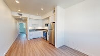 Located at 2375 Old Sonoma Road in Napa, CA, this one-bedroom, one-bathroom unit offers a thoughtfully designed layout across a single floor. The open-concept kitchen and living area is anchored by a well-appointed kitchen featuring crisp white shaker cabinetry, dark countertops, a stainless steel refrigerator, range, and over-the-range microwave. Light wood-style flooring runs throughout the main living areas, lending a clean, contemporary feel and reflecting natural light from the windows. The living area provides a comfortable, functional space that flows seamlessly from the kitchen through a connecting hallway. The bedroom is carpeted for warmth and comfort, featuring a large sliding-door closet for ample storage and a sizable window that frames views of mature surrounding trees, filling the room with natural light. The bathroom is finished in a minimalist style, with wood-style flooring, a white vanity, and a clean, straightforward layout. A dedicated hallway provides practical separation between the living and sleeping spaces. The unit's overall design is modern and understated, with white walls, recessed lighting, and consistent finishes that create a cohesive and welcoming atmosphere throughout.