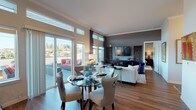 This single-floor residence is thoughtfully designed with an open-concept layout that seamlessly connects the kitchen, dining, and living areas. The kitchen is outfitted with stainless steel appliances, gray shaker-style cabinetry, light quartz countertops, and a pendant-lit island, complemented by hardwood flooring that flows throughout the unit. Clerestory windows and large sliding glass doors flood the space with natural light and provide access to a private outdoor balcony furnished for relaxation, offering views of the surrounding neighborhood.

The living room features crown molding, bold charcoal accent walls, and generous window placement that frames outdoor views, creating a comfortable yet refined atmosphere. The bedrooms offer distinct character — one showcases a deep plum accent wall with decorative wall panels above the headboard, while another includes a wall-mounted split AC unit and direct access to an en-suite bathroom. The primary bath features a dual-sink vanity with light quartz countertops and direct entry into a spacious walk-in closet with multi-tier shelving. A dedicated laundry room with a stacked washer and dryer unit adds everyday convenience to this well-appointed home.