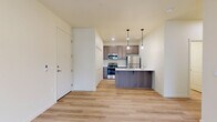 Located in Vancouver, WA, this well-designed 2-bedroom, 2-bathroom unit offers a clean, modern aesthetic throughout its single-floor layout. Light wood-style flooring flows continuously across all rooms, creating a cohesive and airy ambiance. The open living area is bathed in natural light through large windows and a glass-panel entry door, with a wall-mounted mini-split system providing efficient climate control.

The kitchen is a functional centerpiece, featuring warm taupe cabinetry, white quartz countertops, a peninsula island with pendant lighting, and a full suite of stainless steel appliances including a refrigerator, range, and over-the-range microwave. Louvered bi-fold closet doors provide additional pantry-style storage nearby.

Both bedrooms are comfortably sized with large windows that offer views of the surrounding greenery. The primary bedroom includes its own walk-in closet with wire shelving systems, offering generous storage. Each bathroom is thoughtfully appointed with wood-toned vanity cabinetry, white countertops, a tub-shower combination, and light-filled mirrors. The second bathroom mirrors this design with an elongated vanity layout. The overall palette of warm neutrals and natural textures gives the space a fresh, move-in-ready feel.