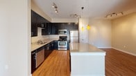 Located at 700 Blue Sky Dr in Concord, NC, this single-floor residence offers a well-designed layout with a cohesive, neutral color palette throughout. The kitchen serves as a standout feature, showcasing dark espresso-toned shaker cabinets paired with light granite countertops, a stainless steel double sink, and a full suite of stainless steel appliances including a gas range, built-in microwave, refrigerator, and dishwasher. A large island with pendant lighting adds both functionality and visual appeal, while warm hardwood-style flooring ties the space together.

The living area is generously proportioned, featuring plush neutral carpet, a ceiling fan, and a sliding glass door that invites natural light. Multiple bedrooms continue the carpeted, light-toned aesthetic, each equipped with ceiling fans and windows fitted with blinds that allow ample daylight. Tray ceiling details add architectural interest to select rooms.

The bathrooms are finished with dark vanity cabinetry, white countertops, framed mirrors, and tub/shower combinations with curved curtain rods. Hardwood-style flooring in the bathrooms complements the overall design. The floor plan flows logically, creating a functional and comfortable living environment throughout.