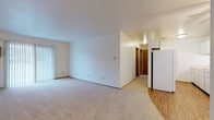 Located at 3728 S 43rd St in Milwaukee, Wisconsin, this single-floor unit offers a straightforward, functional layout designed for comfortable everyday living. The open living area is generously sized, featuring neutral wall-to-wall carpeting and crisp white walls that create a bright, clean atmosphere. Large vertical blinds cover a sliding door that allows natural light to fill the space, enhancing its airy feel. The living area flows naturally toward the kitchen, which is equipped with white cabinetry, white appliances including a refrigerator, and hard-surface flooring. A ceiling fan overhead adds both practicality and a finishing touch to the kitchen area. A hallway with warm-toned wooden doors connects the living spaces to the private rooms. The bedrooms are carpeted and well-proportioned, with one featuring a baseboard heater and a window fitted with blinds, providing natural light and ventilation. The bathroom includes a vanity with a marble-patterned countertop, an undermount sink, white cabinetry with storage drawers, and a large mirror. Throughout the unit, clean white walls and consistent trim detailing provide a cohesive, neutral aesthetic that is easy to personalize. The single-level layout ensures convenient, step-free access throughout the entire space.