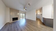 This thoughtfully designed 2-bedroom, 2-bathroom single-floor residence offers a cohesive blend of modern updates and functional living spaces. The open-concept combined dining and living room serves as the heart of the home, featuring warm wood-look flooring, a ceiling fan, a sleek tile-surround fireplace, and a sliding glass door that opens to a private balcony with tree-lined views, filling the space with natural light.

The kitchen is outfitted with gray shaker-style cabinetry, quartz countertops, a chevron tile backsplash, stainless steel appliances, and pendant lighting over a breakfast bar—ideal for both everyday meals and entertaining. An adjacent pantry provides additional storage convenience.

The primary bedroom offers a comfortable footprint with a ceiling fan, a large window framing green outdoor views, and access to a generously sized walk-in closet with built-in shelving and hanging rods. The second bedroom is bright and well-proportioned with the same consistent wood-look flooring found throughout.

Both bathrooms echo the home's modern aesthetic, featuring gray vanities and tile-surround tub-shower combinations. A dedicated laundry nook with washer/dryer connections adds everyday practicality. The hallway entry, accented by a pendant light fixture, provides a welcoming transition into this move-in-ready residence.
