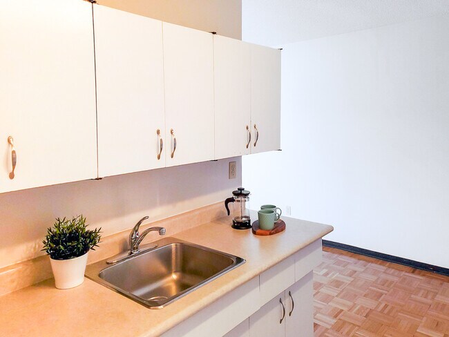 Profitez d'une cuisine lumineuse et fonctionnelle au 1025 Munroe Apartments, dotée d'un grand espace de comptoir et d'armoires modernes - Munroe Manor