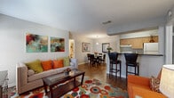 This 2-bedroom, 2-bathroom single-floor residence offers a thoughtfully arranged layout that maximizes its footprint. The open-concept living and dining area serves as the heart of the home, featuring warm hardwood-style flooring throughout. The living room provides ample space for seating and entertainment, with large windows allowing natural light to fill the room, complemented by a front entry door with additional sidelight windows. A dedicated dining area adjoins the living space, illuminated by a pendant light fixture and providing easy access to the kitchen.

The galley-style kitchen is efficiently designed with light maple cabinetry, dark granite-style countertops, and white appliances including a range and refrigerator. A breakfast bar with seating separates the kitchen from the dining and living areas, adding both functionality and an open feel.

Both bedrooms feature plush carpeting, ceiling fans with lighting, and windows dressed with blinds and curtains that allow for natural light and privacy. Each bedroom is served by a closet for added storage.

The two bathrooms are each equipped with a full tub-and-shower combination, tiled surrounds, wood-style flooring, and vanities with dark countertops and wooden cabinetry. Hallways connect the rooms efficiently, completing this functional and comfortable floor plan.