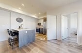 Located in the Edgemont community of Edmonton, Alberta, this thoughtfully designed one-bedroom, two-bathroom unit offers a contemporary living experience across a single level. Light-toned engineered hardwood flooring flows throughout the open-concept main area, complementing the bright white walls and recessed lighting that keep the space feeling airy and well-lit.

The kitchen is a standout feature, showcasing a large waterfall-edge quartz island with seating for three, two-tone cabinetry combining crisp white uppers with warm wood-grain lowers, and a full suite of stainless steel appliances including a French door refrigerator, built-in microwave, and range with tile backsplash.

The living area opens toward a window with neighbourhood views, while a dedicated office nook provides a functional workspace with room for a full desk setup. The primary bedroom is a comfortable retreat with a broad window that draws in natural light and offers views of the surrounding neighbourhood.

Both bathrooms are finished with large-format marble-look porcelain tile flooring and warm wood-toned floating vanities with white quartz countertops. One bathroom features a walk-in shower, while the second includes a full soaker tub. A dedicated closet completes the well-organized layout of this modern Edgemont residence.