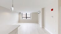 Located at 31 Pratt Street in downtown Hartford, CT, this modern 1-bedroom, 1-bathroom unit offers a clean, contemporary design throughout. The open-concept kitchen and living area is bathed in natural light from large, black-framed windows that frame views of the surrounding Hartford cityscape. Light-toned hardwood flooring runs throughout the main living spaces, complementing the crisp white walls and adding a bright, airy feel to the interior. A wall-mounted mini-split HVAC unit provides efficient climate control directly in the living area.

The kitchen is outfitted with white shaker-style cabinetry featuring black hardware, stainless steel appliances including a full-size refrigerator, electric range, and built-in microwave, as well as sleek white countertops. Recessed and pendant lighting adds a modern touch to the space.

The bedroom is a comfortable, well-proportioned room with plush neutral carpeting, a wall-mounted HVAC unit, large windows overlooking the city, and a full-width closet with bi-fold doors. The bathroom features light tile flooring, a white vanity with a clean white countertop, black accent hardware, and a modern LED-backlit mirror, creating a polished and functional space.