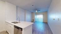 Located at 17645 N Porter Rd in Maricopa, AZ, this single-floor unit offers a thoughtfully designed layout that maximizes functionality within a compact footprint. The open-concept living, dining, and kitchen area serves as the heart of the home, featuring light wood-look flooring, neutral-toned walls, and a ceiling fan that enhances airflow and comfort. A sliding glass door floods the living space with natural light and provides direct access to the private balcony.

The kitchen is well-appointed with white shaker-style cabinetry, crisp white quartz countertops, a subway tile backsplash, and a full suite of stainless steel appliances including a range, microwave, dishwasher, and refrigerator. A peninsula with an undermount sink adds additional prep space and creates a natural separation between the kitchen and living areas.

The bathroom is clean and modern, outfitted with a white vanity, quartz countertop, framed mirror, and a tub-shower combination with floor-to-ceiling white tile surround. Additional conveniences include a dedicated laundry area, a utility room, a closet for storage, and a welcoming entrance. The overall aesthetic is bright, clean, and move-in ready.