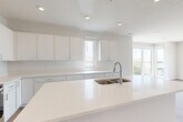 This thoughtfully designed 2-bedroom, 2-bathroom residence in Omaha, Nebraska offers a clean, modern aesthetic throughout. The open-concept kitchen and living area serves as the heart of the home, featuring bright white cabinetry, quartz countertops, a large center island with a double basin sink, and a full suite of stainless steel appliances including a refrigerator, range, microwave, and dishwasher. Recessed lighting and large windows flood the space with natural light, while warm luxury vinyl plank flooring flows throughout the main living areas.

The spacious living room is bathed in natural light from expansive floor-to-ceiling windows, offering pleasant outdoor views of the surrounding Omaha landscape. The generously sized primary bedroom features plush carpeting, a ceiling fan, and direct access to a private en-suite bathroom appointed with a walk-in shower, a white vanity, and warm wood-tone flooring. The second bedroom also offers carpeted floors, a ceiling fan, and its own large window. The second full bathroom includes a soaking tub and shower combination with clean white finishes. A hallway and dedicated closet provide practical storage solutions, completing this well-appointed, move-in-ready residence.