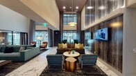 Located at 14175 Dallas Pkwy in Farmers Branch, Texas, this single-story community lobby delivers a refined, hotel-inspired atmosphere with an impressive array of upscale design details. The space is anchored by dramatic double-height ceilings that amplify the sense of openness, while floor-to-ceiling windows line the exterior walls, inviting abundant natural light and offering views of the outdoor pool and surrounding grounds. Underfoot, large-format marble-veined tile spans the majority of the space, lending a polished, contemporary elegance throughout. The main lounge area is thoughtfully arranged with multiple distinct seating vignettes — including plush sofas in teal and olive tones, leather armchairs, and sleek upholstered accent chairs — each positioned atop layered area rugs. A striking textured stone-clad feature wall serves as a focal point, fitted with a wall-mounted television and a linear fireplace insert. Warm wood ceiling accents and a sculptural pendant light fixture add depth and visual interest overhead. A glass-enclosed conference or leasing office sits adjacent to the main lobby, framed in black steel and topped with a rich wood ceiling. A well-appointed cabinetry bar area with stainless steel appliances, mosaic tile backsplash, and marble countertops provides a functional amenity hub. The overall ambiance is contemporary, welcoming, and sophisticated.