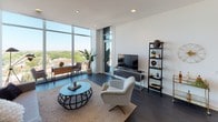 Located at 2518 N Lincoln Ave in Chicago's Lincoln Park neighborhood, this single-floor residence showcases a contemporary design aesthetic defined by clean lines, bright white walls, and dark hardwood flooring throughout. The open-concept living area is anchored by dramatic floor-to-ceiling windows that frame expansive views of the surrounding neighborhood and greenery, flooding the space with natural light.

The kitchen is a standout feature, outfitted with high-gloss white cabinetry extending to the ceiling, stainless steel appliances including a French door refrigerator, a quartz waterfall island with a gas cooktop, and a stainless steel range hood overhead. Bar seating along the island makes it ideal for casual dining and entertaining.

The bedrooms continue the modern theme, each featuring large windows or glass sliding doors opening to a private balcony with sweeping city and treetop views. Ample closet storage and dark hardwood floors maintain a cohesive, refined feel.

The bathrooms are thoughtfully designed with floating vanities, large-format tile flooring, wide mirrors with integrated lighting, and a glass-enclosed walk-in shower in the primary bath. The overall ambiance throughout is calm, contemporary, and polished.