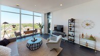 Located at 2518 N Lincoln Ave in Chicago's Lincoln Park neighborhood, this single-floor residence showcases a contemporary design aesthetic defined by clean lines, bright white walls, and dark hardwood flooring throughout. The open-concept living area is anchored by dramatic floor-to-ceiling windows that frame expansive views of the surrounding neighborhood and greenery, flooding the space with natural light.

The kitchen is a standout feature, outfitted with high-gloss white cabinetry extending to the ceiling, stainless steel appliances including a French door refrigerator, a quartz waterfall island with a gas cooktop, and a stainless steel range hood overhead. Bar seating along the island makes it ideal for casual dining and entertaining.

The bedrooms continue the modern theme, each featuring large windows or glass sliding doors opening to a private balcony with sweeping city and treetop views. Ample closet storage and dark hardwood floors maintain a cohesive, refined feel.

The bathrooms are thoughtfully designed with floating vanities, large-format tile flooring, wide mirrors with integrated lighting, and a glass-enclosed walk-in shower in the primary bath. The overall ambiance throughout is calm, contemporary, and polished.