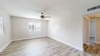 This well-maintained single-floor residence has been thoughtfully updated throughout, offering a clean, move-in-ready interior with a consistent light and airy aesthetic. The flooring is a standout feature, with wood-look planks in warm neutral tones running seamlessly through every room, lending continuity and a modern touch to the entire space.

The living area is generously proportioned, bathed in natural light from multiple windows fitted with blinds. A ceiling fan with a brushed metal finish provides both style and comfort overhead, while crisp white walls and clean baseboards contribute to the bright, open atmosphere.

The kitchen is efficiently laid out and fully equipped with white shaker-style cabinetry, light quartz-style countertops, a undermount sink with a gold-toned faucet, a stainless steel refrigerator, an electric range with overhead ventilation, and a dishwasher — offering all essential appliances in a cohesive, updated package.

The bedrooms are well-sized with large windows that invite natural light and views of surrounding greenery. One bedroom features a sliding double-door closet with built-in shelving, providing practical storage solutions.

The bathroom is clean and functional, featuring a tub-shower combination, a white vanity with a stone-look countertop, a wood-framed mirror, and gold-accented fixtures that echo the warm hardware tones found throughout the home.