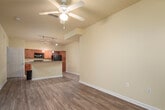 This single-floor residence at 1214 Continental Dr in Madison, Alabama offers a well-designed open-concept layout with warm, neutral tones and wood-look flooring carried consistently throughout the space. The living area is generously proportioned, featuring vaulted ceilings and a ceiling fan that enhances airflow and comfort. Large windows and a front entry door with sidelights flood the space with natural light and provide views of the surrounding greenery.

The kitchen is a functional centerpiece of the home, anchored by a peninsula with granite-style countertops and pendant lighting overhead. Rich medium-toned cabinetry lines the walls alongside a full suite of black appliances, including a refrigerator, range, and microwave. Track lighting adds additional illumination to the workspace, and a wine rack built into the upper cabinetry adds a distinctive touch.

The bedroom features its own ceiling fan and window, maintaining the consistent flooring and light color palette found throughout the home. The bathroom is well-appointed with rich wood-toned cabinetry, a granite-style countertop, an undermount sink, and a full tub-shower combination with tile surround. Clean white fixtures and chrome hardware complete the polished look. Overall, the space presents a cohesive, move-in-ready interior with practical finishes and an inviting, open feel.
