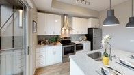This single-floor residence is thoughtfully designed with a clean, contemporary aesthetic carried throughout each space. Light-toned wood-style flooring runs continuously through the unit, creating a cohesive and airy feel. The living area offers a comfortable, open layout with neutral walls, a large window that brings in natural light, and pleasant outdoor views of surrounding greenery and the wider cityscape. The space accommodates a seating arrangement with ample room to move.

The kitchen is a standout feature, outfitted with crisp white cabinetry, stone-look countertops, stainless steel appliances including a range with a sleek wall-mounted hood, and a herringbone-patterned tile backsplash. A peninsula with an integrated sink provides additional workspace and casual dining potential. A sliding glass door leads directly from the kitchen to a private balcony, extending the living space outdoors.

The bedroom is calm and well-proportioned, with soft neutral tones, a closet with hanging storage, and its own entry door. The bathroom features a white vanity with a clean countertop, a mirror, and a shower with a curtain, all finished with matching wood-look flooring and neutral gray walls.