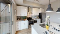 This single-floor residence is thoughtfully designed with a clean, contemporary aesthetic carried throughout each space. Light-toned wood-style flooring runs continuously through the unit, creating a cohesive and airy feel. The living area offers a comfortable, open layout with neutral walls, a large window that brings in natural light, and pleasant outdoor views of surrounding greenery and the wider cityscape. The space accommodates a seating arrangement with ample room to move.

The kitchen is a standout feature, outfitted with crisp white cabinetry, stone-look countertops, stainless steel appliances including a range with a sleek wall-mounted hood, and a herringbone-patterned tile backsplash. A peninsula with an integrated sink provides additional workspace and casual dining potential. A sliding glass door leads directly from the kitchen to a private balcony, extending the living space outdoors.

The bedroom is calm and well-proportioned, with soft neutral tones, a closet with hanging storage, and its own entry door. The bathroom features a white vanity with a clean countertop, a mirror, and a shower with a curtain, all finished with matching wood-look flooring and neutral gray walls.