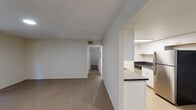 This single-floor residence offers a clean, functional layout designed for comfortable everyday living. The open living area is finished with warm wood-look flooring and neutral white walls, creating a bright and versatile space. A sliding glass door floods the room with natural light and provides access to an outdoor area, enhancing the sense of openness throughout.

The galley-style kitchen is thoughtfully outfitted with white shaker cabinetry, dark countertops, and stainless steel appliances including a refrigerator and electric range. Under-cabinet lighting and a large overhead flush light keep the space well-lit and practical. A peninsula counter connects the kitchen to the living area, offering a natural transition between spaces.

The bedrooms are carpeted for comfort and feature neutral tones, large windows that invite natural light, and mirrored sliding closet doors that add depth and storage. A dedicated hallway connects the private areas of the residence to the main living spaces.

The bathroom is finished in a crisp, all-white palette with a tiled shower-tub combination, a white vanity with brushed nickel hardware, and light wood-look flooring, delivering a clean and refreshed aesthetic. Overall, the residence presents a cohesive, move-in ready environment with a simple, modern sensibility throughout.
