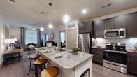 This single-floor residence offers a thoughtfully designed open-concept layout that seamlessly connects the kitchen, dining, and living areas. The kitchen is a standout feature, showcasing dark espresso cabinetry, granite countertops, a subway tile backsplash, and a full suite of stainless steel appliances including a refrigerator, range, and microwave. A spacious granite-topped island with pendant lighting serves as both a prep area and a casual dining spot with bar seating. Wood-look flooring runs throughout the main living areas, adding warmth and continuity to the space.

The living room is bright and inviting, benefiting from natural light through large windows dressed with blinds and drapes. A ceiling fan adds comfort and function to the room. A dedicated dining area provides additional space for formal meals.

The primary bedroom is carpeted and generously sized, featuring large windows that invite natural light. A second bedroom offers a similarly comfortable and well-lit retreat. The bathroom is elegantly finished with granite countertops, dark cabinetry, wood-look flooring, and a glass-enclosed shower. An adjacent walk-in closet with built-in shelving provides practical storage. Throughout the residence, neutral tones and modern finishes create a cohesive and contemporary ambiance.
