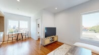 Located at 100 Tuers Ave in Jersey City, NJ, this thoughtfully designed 2-bedroom, 2-bathroom residence combines modern finishes with a clean, contemporary aesthetic throughout its single-floor layout. Warm hardwood flooring flows consistently across every room, anchoring the bright, neutral palette defined by crisp white walls and recessed lighting.

The kitchen-living area serves as the heart of the home, featuring a well-appointed kitchen with two-tone cabinetry — pairing light natural wood with sleek matte gray uppers — white quartz countertops, a striking marble-style backsplash, and stainless steel appliances including a gas range and built-in dishwasher. A large picture window floods the dining nook with natural light while framing impressive views of the Jersey City and New York City skyline.

The living room is cozy yet functional, with a bright window offering neighborhood views and a wall-mounted mini-split system for climate control. Both bedrooms are comfortable, well-lit spaces with hardwood floors, natural light from exterior-facing windows, and wall-mounted mini-split units.

The two bathrooms are finished with wood-look tile, speckled stone-style surfaces, and modern vanities with clean white countertops — one featuring a soaking tub and shower combination, the other a sleek walk-in shower stall. The overall ambiance is modern, airy, and move-in ready.