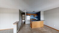 Located in Marion, Iowa, this single-floor unit offers a functional and straightforward layout designed for comfortable everyday living. The kitchen is a standout feature, showcasing warm honey-toned oak cabinetry, dark granite-style countertops, and a bold navy accent wall that adds a pop of color. A large peninsula provides additional prep space and casual seating, while tile flooring and included appliances — including a refrigerator and range — complete the space. The kitchen flows openly toward the main living and dining areas, where large windows and sliding glass door access to a balcony bring in generous natural light and outdoor views of surrounding trees and neighboring rooftops. Bedrooms are carpeted for comfort, finished with neutral gray walls, warm wood-trimmed doors, and ceiling fans for climate control. Baseboard heating runs throughout the unit, and select rooms feature wall-mounted air conditioning units. The layout, as seen in the dollhouse view, is well-organized with clearly defined living, kitchen, and sleeping zones connected by a central hallway. Warm wood baseboards and trim provide a consistent, cohesive aesthetic throughout this practical Marion residence.