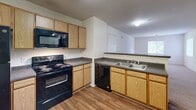 This single-floor, two-bedroom, two-bathroom home at 830 Allonby Dr in Fayetteville, NC offers a practical and comfortable layout. The combined kitchen and living area serves as the heart of the home, featuring warm wood-tone cabinetry, dark countertops, and a full suite of black appliances including an electric range, built-in microwave, dishwasher, and refrigerator. Durable wood-look flooring runs throughout the kitchen and living space, providing an easy-to-maintain foundation.

Both bedrooms are carpeted and filled with natural light from windows fitted with blinds. The primary bedroom is notably spacious and includes a walk-in closet with built-in shelving, a ceiling fan, and direct access to the hallway. The second bedroom also features a ceiling fan and a window with an outdoor view. Three closets total provide ample storage throughout the home.

The two bathrooms offer functional designs, with one featuring a full soaking tub with chrome fixtures and a clean white surround. The bathrooms are finished with wood-look flooring consistent with the rest of the home. An in-unit laundry area adds everyday convenience. Neutral wall tones and consistent finishes create a cohesive, move-in-ready feel throughout the entire space.