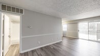 This one-bedroom, one-bathroom residence in Indianapolis, IN offers a thoughtfully designed single-floor layout that maximizes comfort and functionality. The open living room is a standout feature, with wood-style plank flooring in a cool gray tone, neutral gray walls accented by white chair rail molding, and a textured ceiling. A sliding glass door floods the space with natural light and provides access to the outdoors, creating an airy, welcoming atmosphere.

The kitchen is efficiently arranged in a galley style, featuring rich dark wood cabinetry with brushed nickel hardware, white countertops, a stainless steel sink, and full appliances including a refrigerator — all set on matching wood-style flooring.

The bedroom is a comfortable, quiet retreat with the same plank flooring, soft neutral walls, a window with natural light, and a ceiling vent for climate control. Two closets offer generous storage throughout the unit.

The bathroom is clean and functional, featuring a full tiled tub and shower combo with chrome fixtures, a dark wood vanity with a speckled stone countertop, and wood-style flooring that ties the space together cohesively. Overall, the residence presents a modern, neutral palette ideal for easy personalization.