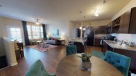 Located at 11211 Westwood Loop in San Antonio, TX, this single-story unit offers a well-designed open-concept floor plan that seamlessly connects the living, dining, and kitchen areas. Rich hardwood-style flooring flows throughout the main living spaces, creating a warm and cohesive aesthetic.

The kitchen is outfitted with dark espresso cabinetry, granite-style countertops, black appliances, and a central island with bar seating — illuminated by stylish pendant lighting overhead. Adjacent to the kitchen, a dedicated dining area accommodates a full-sized table and provides convenient access to an in-unit laundry closet housing a full-size washer and dryer.

The living room is bright and inviting, featuring a ceiling fan, large windows that allow natural light to filter in, and ample space for comfortable seating arrangements.

The unit includes two well-proportioned bedrooms, each appointed with plush carpeting, ceiling fans, and windows with natural light. The primary bedroom offers a calm, restful atmosphere with generous closet access. The bathrooms feature dark vanity cabinetry with dark countertops and hardwood-style flooring, with one bathroom including a tub-shower combination.