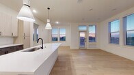 This single-floor space showcases a thoughtfully designed open-concept layout that seamlessly connects the kitchen, dining, and living areas. Light hardwood flooring flows consistently throughout, lending warmth and cohesion to the interior. The kitchen serves as a central focal point, featuring a large island with a white quartz countertop, a matte black faucet with an undermount sink, and stylish pendant lighting overhead. Two-toned cabinetry — light wood uppers paired with darker lower cabinets — frames a white tile backsplash, while stainless steel appliances, including a French door refrigerator, gas range, and built-in microwave, complete the well-equipped space.

The living area is generously proportioned, bathed in natural light from multiple windows and a glass-paneled exterior door that frames views of the surrounding skyline and landscape. A ceiling fan adds practical comfort to the space.

The bathroom is finished with large-format white tile flooring, a sleek vanity with dark hardware, and a full bathtub surrounded by marble-style tile. A dedicated closet area with built-in shelving and hanging rods provides organized storage. Additional bedrooms feature hardwood floors, bright windows, and clean white walls, maintaining the space's consistent modern aesthetic throughout.