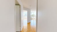 This well-appointed one-bedroom, one-bathroom unit at 5600 Sheppard Ave, Unit 517, offers a thoughtfully organized single-floor layout. The living room is a standout space, featuring classic parquet hardwood flooring and expansive floor-to-ceiling windows with a sliding glass door that opens to a balcony, flooding the room with natural light and framing open city views. The bright, airy atmosphere is enhanced by clean white walls and a textured ceiling.

The generously sized primary bedroom also features the same warm parquet flooring, neutral tones, and a built-in closet with sliding doors, providing ample storage. A second image of this room highlights its open, flexible layout and connection to the hallway.

The kitchen is compact yet functional, equipped with stainless steel appliances including an LG over-the-range microwave and an electric range, complemented by subway tile backsplash, white cabinetry, and light countertops — a clean, modern aesthetic throughout.

The bathroom is finished with large-format tile flooring, a white vanity with under-sink storage, a framed mirror, and a well-lit three-bulb fixture above, alongside a shower-tub combination. A welcoming hallway connects all rooms, contributing to the unit's efficient and practical flow.