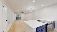 Located in Austin's vibrant 78704 neighborhood, this thoughtfully updated 2-bedroom, 2-bathroom residence offers a clean, modern aesthetic throughout its single-floor layout. Light wood-tone flooring flows seamlessly across the entire space, creating a warm and cohesive feel from room to room.

The open-concept kitchen and living area serves as the heart of the home. The kitchen stands out with striking navy blue cabinetry, white quartz countertops, a classic white subway tile backsplash, stainless steel appliances, and a peninsula that opens directly into the living room. A pendant chandelier and recessed lighting illuminate the living area, which benefits from natural light and outdoor views through a sliding glass door fitted with vertical blinds and a ceiling fan overhead.

Both bedrooms are comfortably sized, featuring the same light wood flooring, ceiling fans, and clean white walls. The primary bedroom includes a built-in closet and direct access to a dedicated bathroom. The second bedroom is bright and versatile, served by its own full bathroom.

Both bathrooms share a cohesive design with large-format white wall tiles, soaking tub-shower combinations, matte black fixtures, and navy blue accent cabinetry, tying the home's bold color palette together with functional elegance.