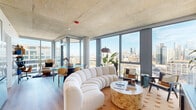 Located at 1114 West Carroll Avenue in Chicago's vibrant West Loop neighborhood, this three-bedroom, two-bathroom residence offers a compelling blend of industrial-modern design and contemporary comfort. Exposed concrete ceilings throughout lend an authentic urban character, while light hardwood flooring grounds the space with warmth.

The living area is a standout, wrapped in floor-to-ceiling windows that frame breathtaking panoramic views of the Chicago skyline, flooding the interior with natural light. A dining area sits adjacent, making the open layout ideal for both everyday living and entertaining.

Each of the three bedrooms benefits from expansive window walls with commanding city views. The generously sized primary bedroom features a well-organized walk-in closet with adjustable shelving and hanging systems. The two bathrooms are finished in a clean, modern palette — one showcasing a glass-enclosed walk-in shower with white subway tile and matte black fixtures, and the other offering equally refined, neutral finishes.

The hallway connects the living and private spaces efficiently, and an in-unit stacked washer and dryer adds everyday convenience. Throughout, the design maintains a cohesive aesthetic — crisp white walls contrasting with raw concrete and warm wood — creating a sophisticated, urban retreat in the heart of Chicago.