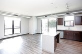 This well-appointed single-floor unit showcases a contemporary design with thoughtful finishes throughout. The open-concept kitchen is a standout feature, boasting rich dark-espresso cabinetry, light granite-style countertops, a white subway tile backsplash, and a full suite of stainless steel appliances including a refrigerator, range, and built-in microwave. A central island with pendant lighting overhead adds both function and style, while large windows invite an abundance of natural light.

The living area features wood-look plank flooring and exposed ductwork that lends an industrial-modern aesthetic, complemented by generous windows offering outdoor views of the surrounding urban landscape and greenery.

The bedrooms are carpeted for comfort and include large windows that frame views of the neighborhood. Each bedroom benefits from dedicated walk-in closet space, equipped with wire shelving systems that maximize storage capacity.

Two bathrooms serve the unit, each finished with dark vanity cabinetry, granite-style countertops, and wood-look flooring. One bathroom features a tub-shower combination, while the second offers a clean, functional layout with a windowed vanity area. The consistent use of quality materials and a neutral color palette gives the entire space a cohesive, modern feel.