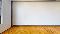 Located on the 5th floor at 101 E Sixth St in downtown Winston-Salem, this 1-bedroom, 2-bathroom loft-style unit blends industrial character with modern finishes. Original hardwood floors and exposed steel beams run throughout, while large multi-pane industrial windows flood the open living area with natural light and offer city views. The kitchen features rich dark cabinetry, granite countertops, a stainless steel sink, and stainless steel appliances. The spacious bedroom includes two generous closets with built-in shelving. Both bathrooms are finished with dark tile flooring, dark wood vanities with granite counters, and tub-shower combinations. Exposed ductwork adds to the unit's urban, loft aesthetic.
