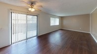Located in the Arbor Park community of Long Beach, California, this single-story unit offers a practical and comfortable layout throughout. A clean, well-lit hallway with rich dark hardwood-style flooring provides a welcoming entry into the space.

The open living and dining area is a standout feature, showcasing the same dark hardwood-style floors, a textured ceiling with a ceiling fan, and an abundance of natural light streaming through large windows fitted with vertical blinds. A sliding glass door leads directly to an outdoor area, enhancing the connection to the surroundings. A pass-through counter connects the living area to the kitchen, promoting an open flow between spaces.

The kitchen is well-appointed with white cabinetry, light speckled countertops, a double-basin sink, a dishwasher, and a range, along with a window that brings in additional natural light.

The bedrooms feature plush wall-to-wall carpeting, warm neutral-toned walls, textured ceilings, and windows with vertical blinds that allow for natural light and privacy.

The bathrooms are finished with white cabinetry, speckled countertops, large vanity mirrors, and a tiled shower-tub combination, complemented by the consistent dark hardwood-style flooring found throughout the common areas.