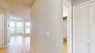 This single-story space is thoughtfully laid out, offering a comfortable and functional floor plan visible across its main living areas, kitchen, bedrooms, and bathroom. The living room serves as the central gathering space, featuring light ceramic tile flooring, a ceiling fan, a textured ceiling, and a tile-surround fireplace flanked by large windows fitted with blinds that allow generous natural light to filter in. Adjacent to the living area, the dining space is defined by warm-toned tile flooring, a pendant light fixture, and a curved half-wall that separates it from the kitchen, adding architectural interest.

The kitchen is well-appointed with warm wood-toned cabinetry offering ample storage, stainless steel appliances including a refrigerator, range, microwave, and dishwasher, light tile countertops, and tile flooring that continues the cohesive design. The bedrooms feature wood-look plank flooring, neutral wall tones, ceiling fans, and windows that bring in outdoor views and natural light. A hallway connects the bedroom areas and leads to the bathroom, which includes a single-vanity with wood cabinetry, a tub and shower combination, tile flooring, and a lighted mirror. Throughout the space, textured ceilings and neutral tones create a consistent, understated ambiance.