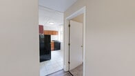 Located in Chicago's Hyde Park neighborhood, this one-bedroom, one-bathroom unit on S Kimbark Avenue offers a practical and well-organized layout across a single floor. A welcoming hallway connects the rooms and sets the tone for the space's straightforward, functional design.

The kitchen is a standout feature, outfitted with warm-toned wood cabinetry that extends to the ceiling for generous storage, a full suite of black appliances including a refrigerator and gas range, a single-basin sink, and light countertops. White tile flooring and a drop ceiling with recessed panel tiles give the kitchen a clean, utilitarian feel, while a window allows for natural light.

The bedroom features neutral beige walls, soft carpeted flooring, and direct access to the bathroom, creating a convenient en-suite-style flow. The closet provides dedicated storage space.

The bathroom is finished in an all-white palette with tile flooring, a full soaking tub with shower, a white vanity with under-cabinet storage, an oval mirror, and a frosted window that brings in diffused natural light while maintaining privacy.

Overall, this unit presents a compact yet complete living space with a neutral color scheme, functional fixtures, and a well-connected layout suited for everyday living in a classic Chicago residential setting.