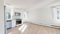 Located in the heart of Vancouver's West End at 1320 Bute Street, this efficiently designed studio offers a thoughtful layout across a single floor. The combined kitchen and living area forms the heart of the unit, bathed in natural light streaming through multiple windows and large sliding glass doors that open onto a private balcony overlooking the surrounding cityscape and greenery.

The kitchen is well-appointed with crisp white cabinetry extending to the ceiling, a herringbone-patterned tile backsplash, and a full suite of stainless steel appliances including a refrigerator, electric range, over-the-range microwave, and dishwasher. Light-toned laminate flooring runs throughout, lending continuity and a clean, modern aesthetic to the open living space.

The bathroom features floor-to-ceiling white subway tile surrounding a soaker tub and shower combination, complemented by stone-look floor tile, a white vanity with quartz-style countertop, and chrome fixtures — delivering a fresh, classic finish. A dedicated closet provides convenient in-unit storage. A textured ceiling and baseboard heating are consistent throughout the unit. The sliding door access to the balcony enhances the sense of space and provides an outlook to the vibrant neighbourhood beyond.