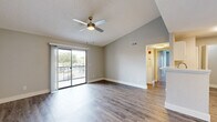 Located in Orlando, FL, this 2-bedroom, 2-bathroom residence offers a well-designed single-floor layout that maximizes comfort and functionality. The open-concept living and dining area features vaulted ceilings and durable wood-look flooring, creating a bright and airy atmosphere. A ceiling fan and sliding glass doors lead to a private patio, flooding the space with natural light and providing outdoor access with pleasant views.

The galley-style kitchen is thoughtfully appointed with white shaker cabinetry, light stone-look countertops, a central island with a sink, and a full suite of stainless steel appliances including a refrigerator, electric range, microwave, and dishwasher. A pantry provides additional storage convenience.

Both bedrooms are carpeted for comfort and include ceiling fans and ample natural light from large windows. The primary bedroom offers generous proportions with access to natural views. The two bathrooms are finished with white cabinetry, stone-look countertops, and tub-shower combinations.

Additional highlights include a dedicated laundry area, multiple closets for storage, and a hallway connecting the private and communal areas of the home seamlessly. The neutral color palette throughout creates a clean, move-in-ready aesthetic.