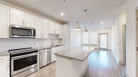 Located in Bradenton, FL, this thoughtfully designed 2-bedroom, 2-bathroom single-floor home offers a clean, modern aesthetic throughout. The open-concept kitchen serves as the heart of the home, showcasing white shaker cabinetry, a classic subway tile backsplash, granite countertops, and a large central island with pendant lighting overhead. Stainless steel appliances — including a French door refrigerator, range, microwave, and dishwasher — complete the well-equipped space. Light wood-style flooring flows seamlessly from the kitchen into the bright living area, which benefits from abundant natural light through large windows and a glass-paneled exterior door. Both bedrooms are carpeted and offer a quiet, comfortable retreat, each with access to a dedicated closet featuring wire shelving systems. The primary bathroom is a standout, offering a granite-topped vanity, wood-look tile flooring, large-format wall tile, and a glass-enclosed walk-in shower. Recessed lighting throughout the home adds a polished, contemporary feel, while neutral wall tones create a versatile canvas. This well-appointed home combines modern finishes with a functional layout in a desirable Bradenton location.